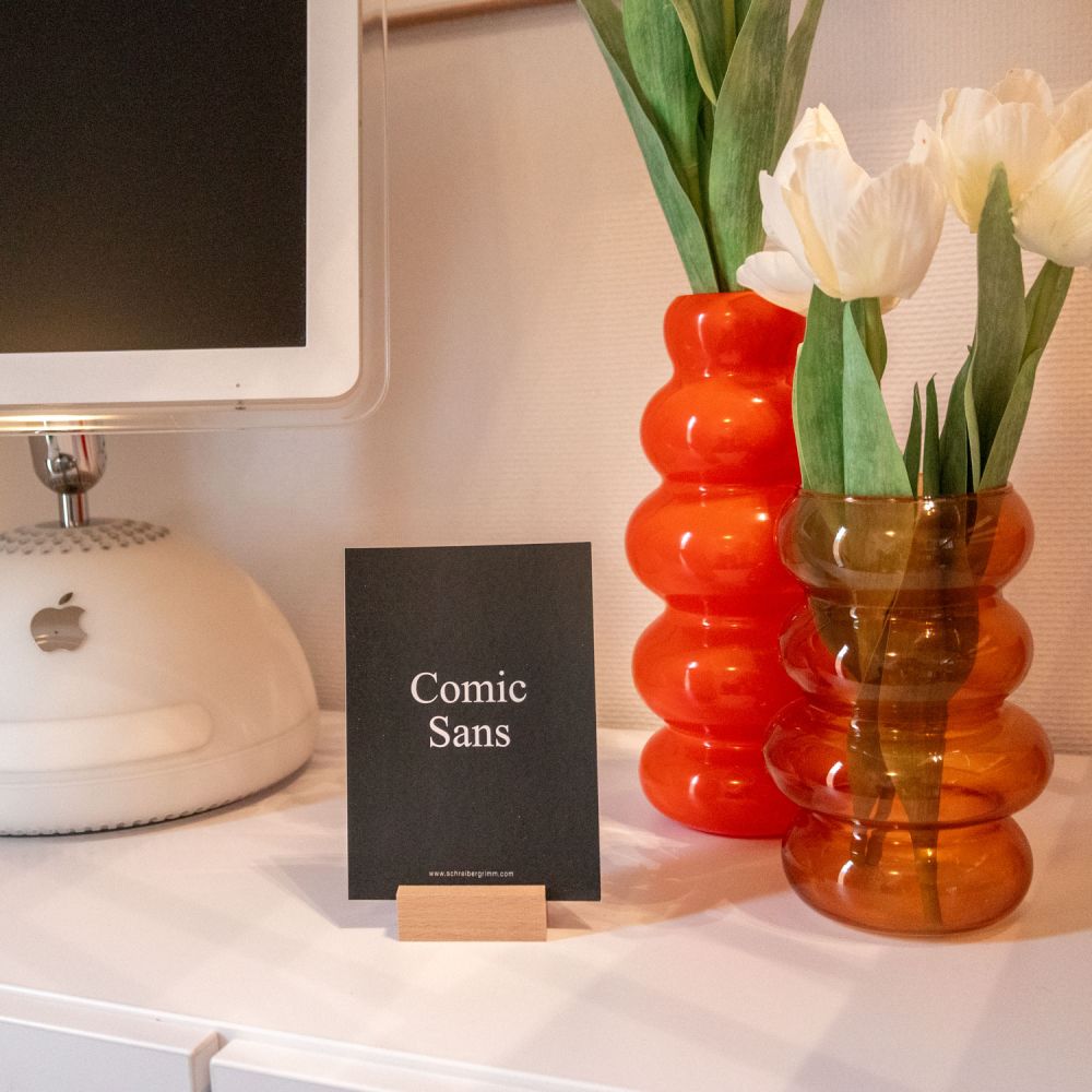 Comic Sans Karte dekorativ vor einem alten weißen Mac und orangefarbenden Bubble Vase mit Tulpen