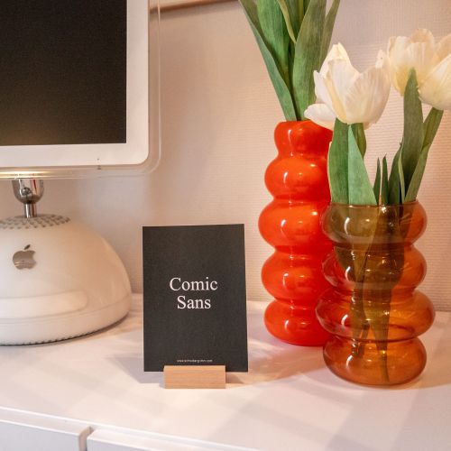 Comic Sans Karte dekorativ vor einem alten weißen Mac und orangefarbenden Bubble Vase mit Tulpen